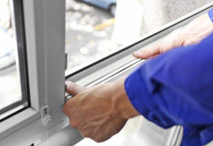 Construction worker putting sealing foam tape on window in house